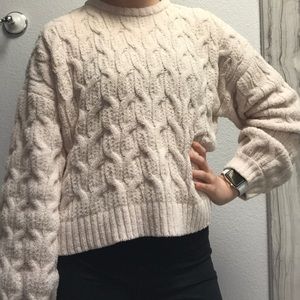 A women’s light pink cable sweater